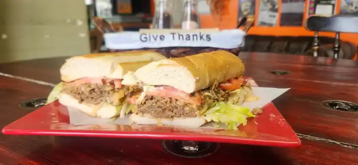 Philly Cheese Steak — French roll, beef or chicken, grilled onion, green & red peppers, cheese, lettuce, tomato, and mayo