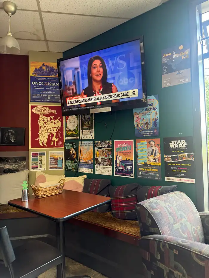 The community poster wall at Blue Heron, covered with flyers for local theatre, art walks and neighborhood concerts, above a wooden booth